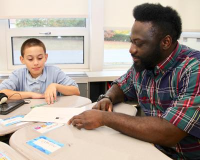 帕拉教育家 at table helping elementary student